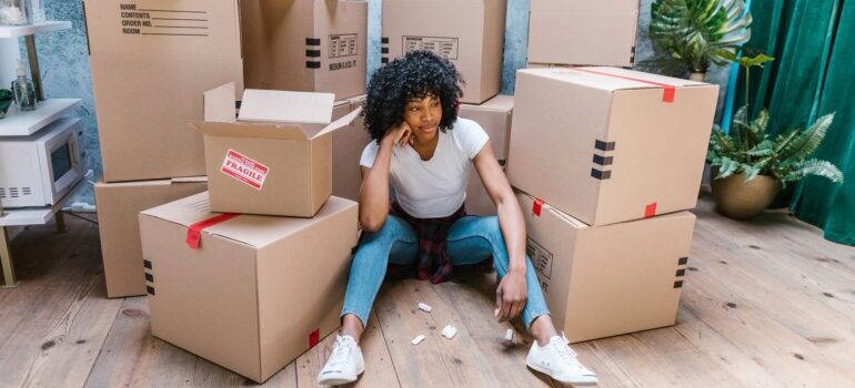 A girl sitting between moving boxes 
