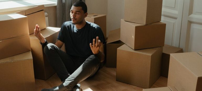 Man meditating next to moving boxes