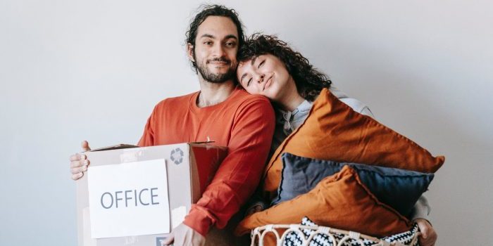 A man and a woman trying to pack and move office equipment 